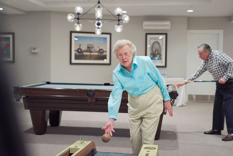 senior woman playing skeeball at The Merion