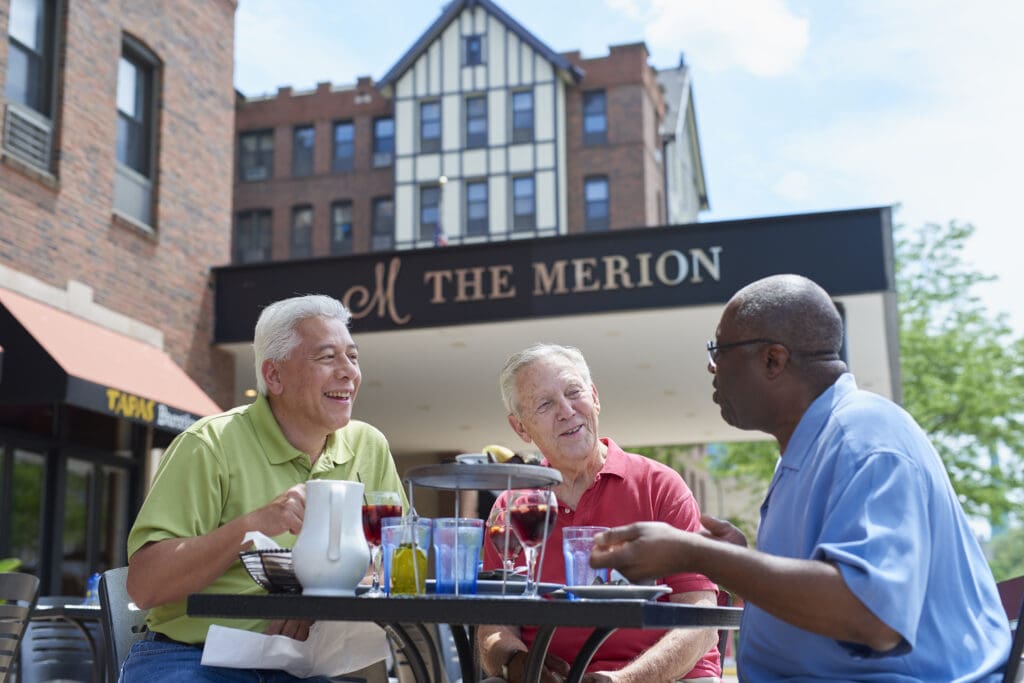three senior gentlemen enjoy outside dining at The Merion