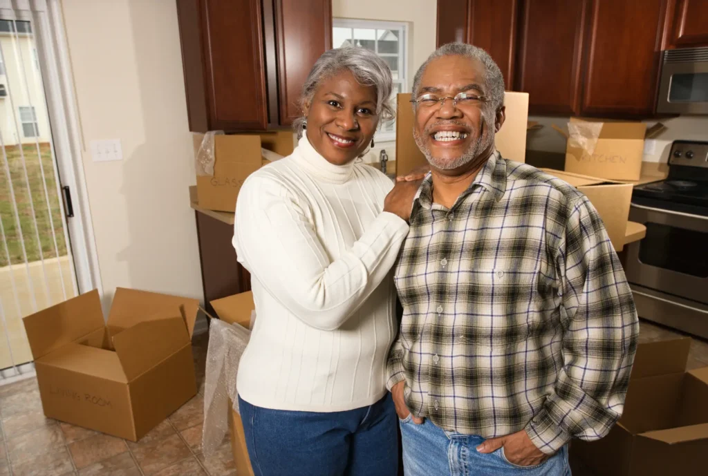 Portrait of senior African-American couple in kitchen with moving boxes.