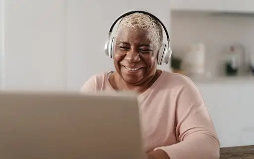 An elderly black woman enjoying an online class on her laptop as a part of the initiative to improve lifelong learning for seniors at The Merion.