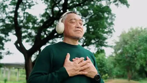 Stress Management For Seniors in a Comumunity 1 An older adult with headphones on walking on the campus of The Merion in Evanston, IL, working on stress management for seniors.