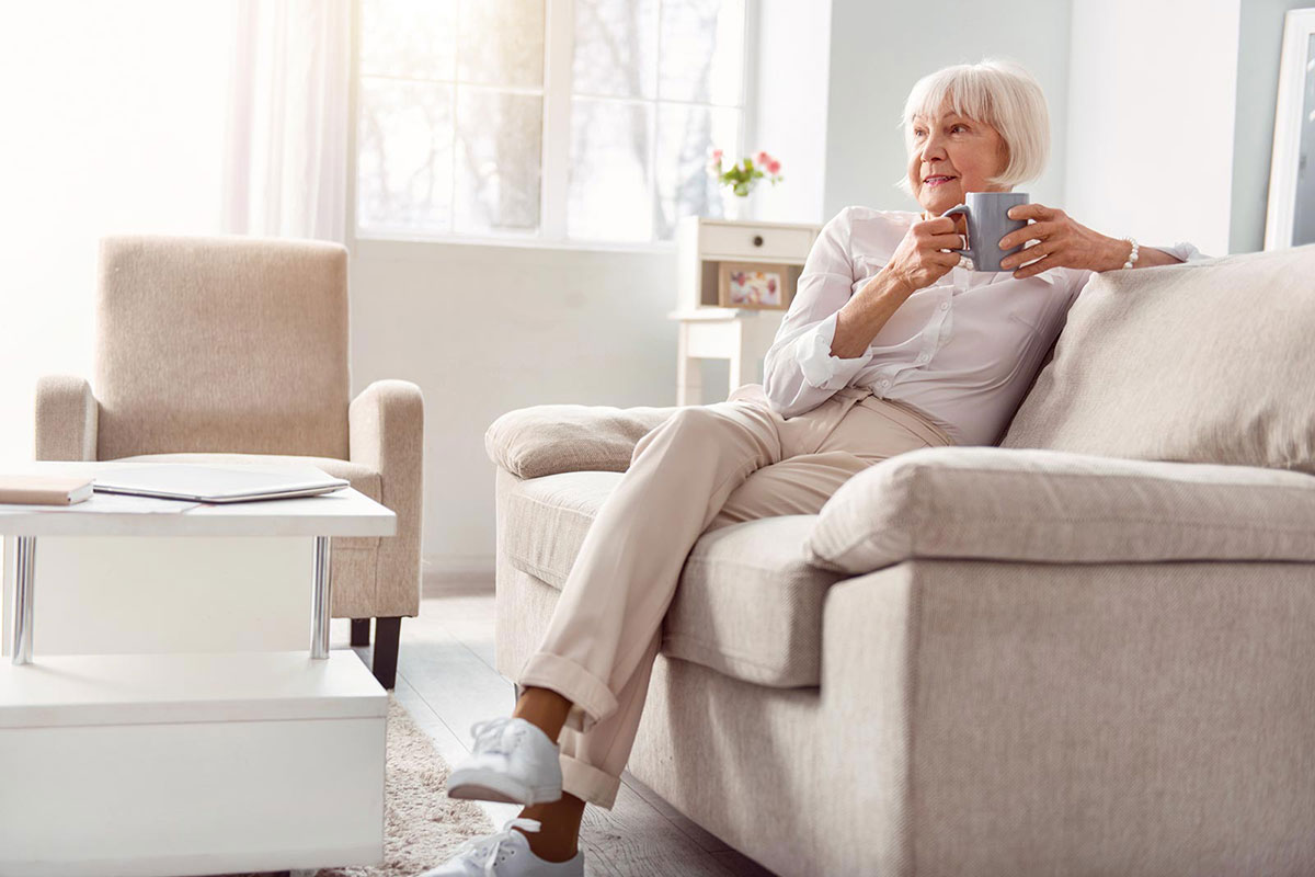 Senior woman sipping coffee on a couch