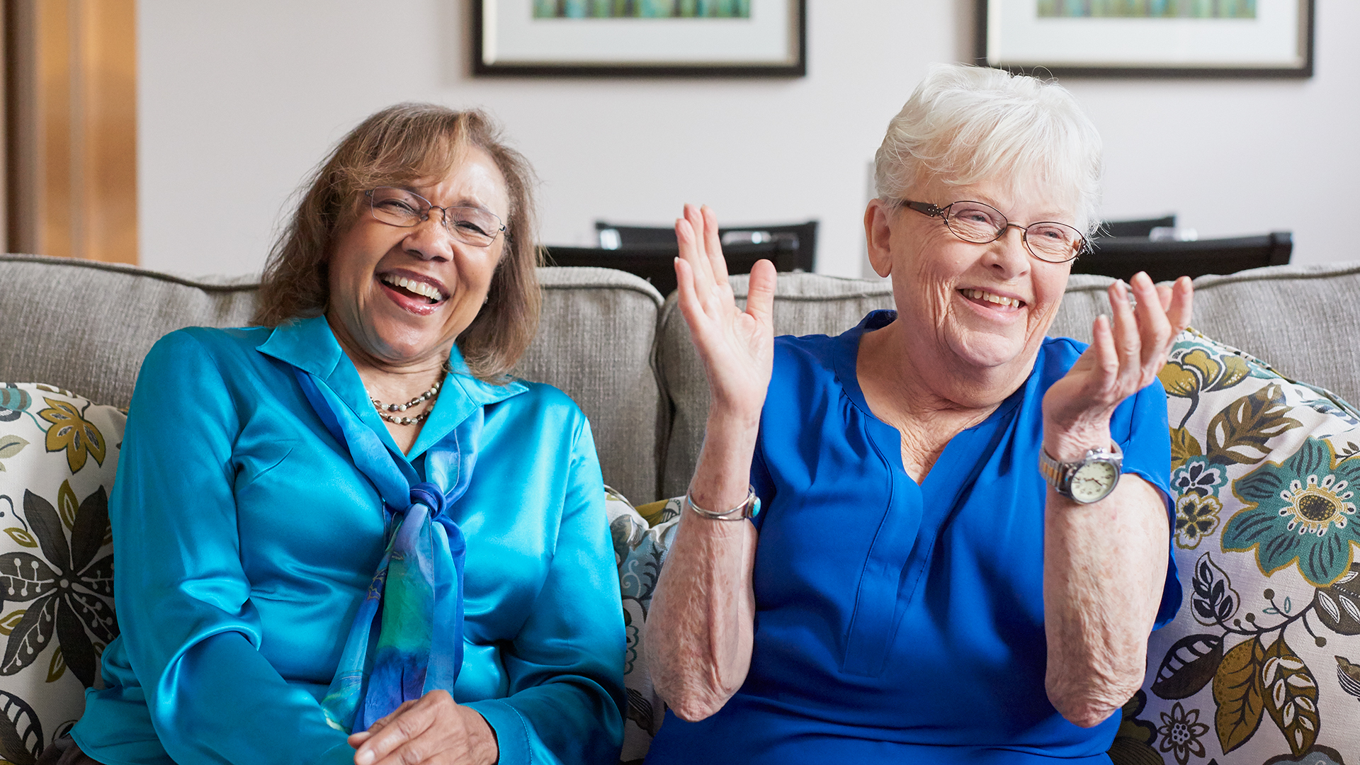 senior women sitting on a couch laughing together